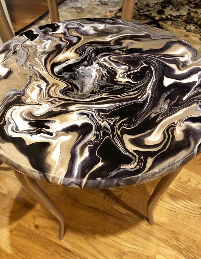 a black and white marbled table with two chairs in the backgrounge