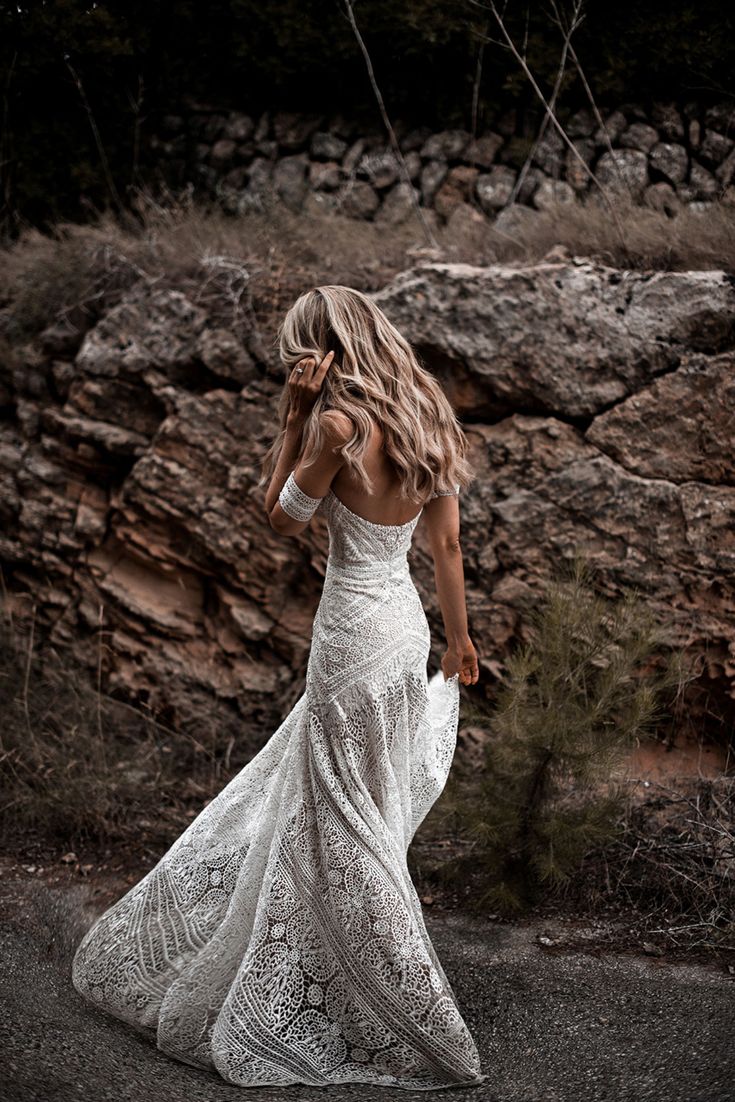 a woman in a white dress walking down the road with her back to the camera