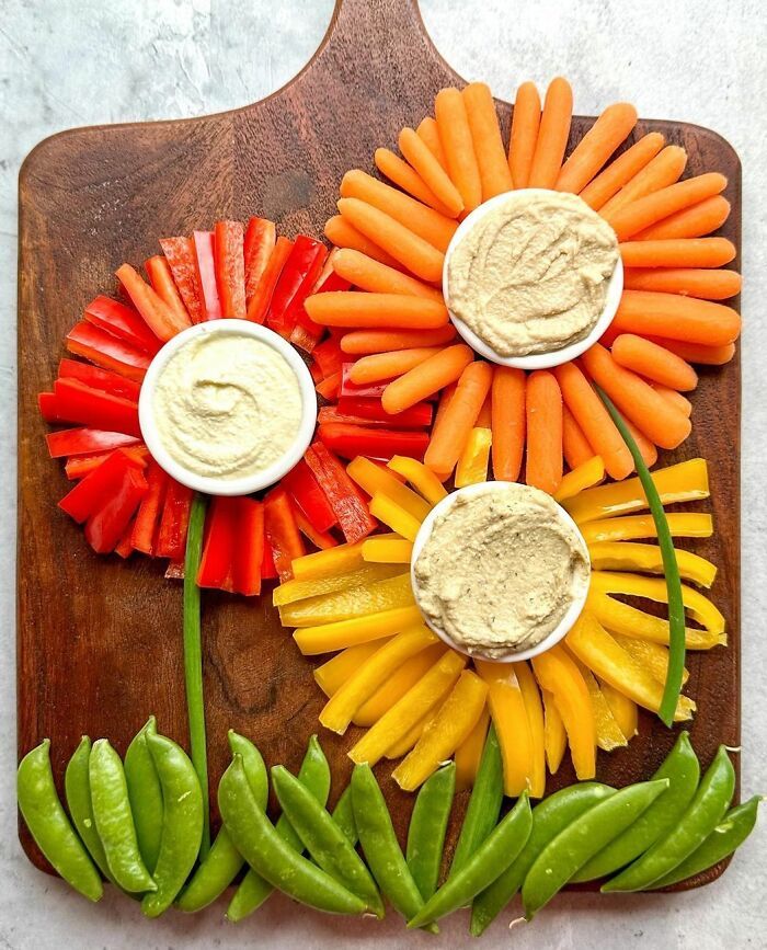 carrots, celery and peppers on a cutting board with dip in the middle