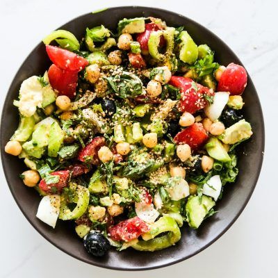 a black bowl filled with lots of different types of food on top of a white table