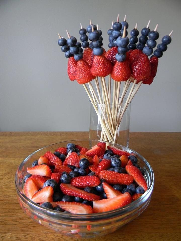 strawberries and blueberries in a glass bowl on a wooden table with toothpicks