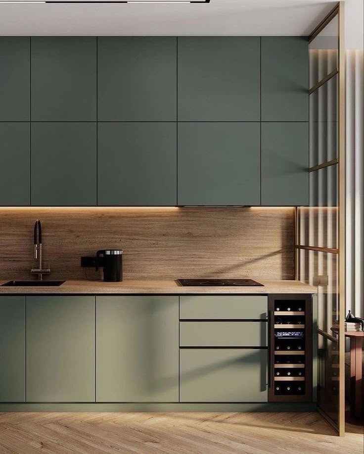 a modern kitchen with green cabinets and wood flooring is pictured in this image, there is also a wine rack on the counter