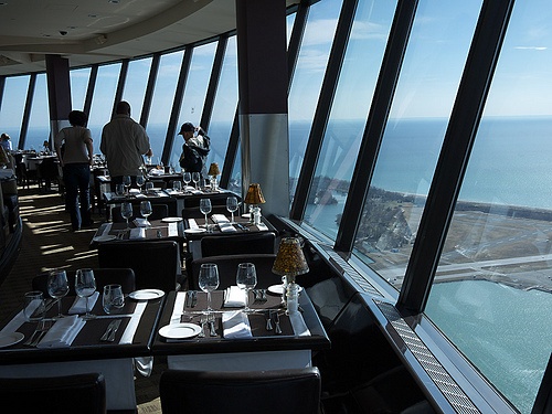 people are standing at the top of a restaurant looking out over the ocean and land