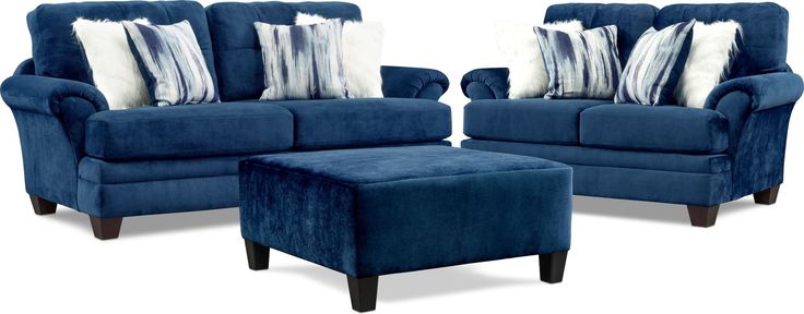 two blue chairs and a footstool with pillows on them