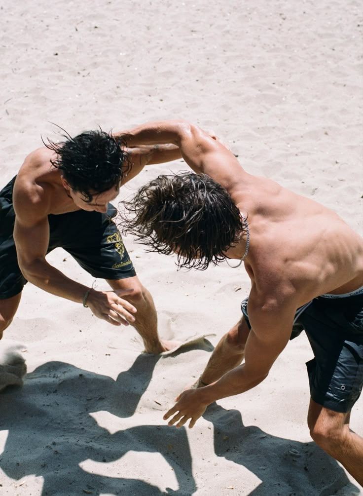 two men are playing frisbee in the sand