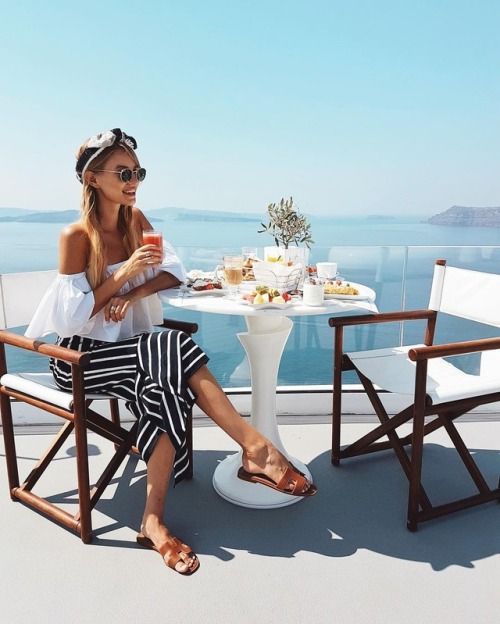 a woman sitting at a table on top of a boat eating food and drinking coffee