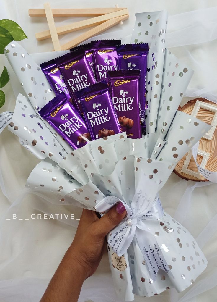 a hand holding a bouquet of chocolate bars