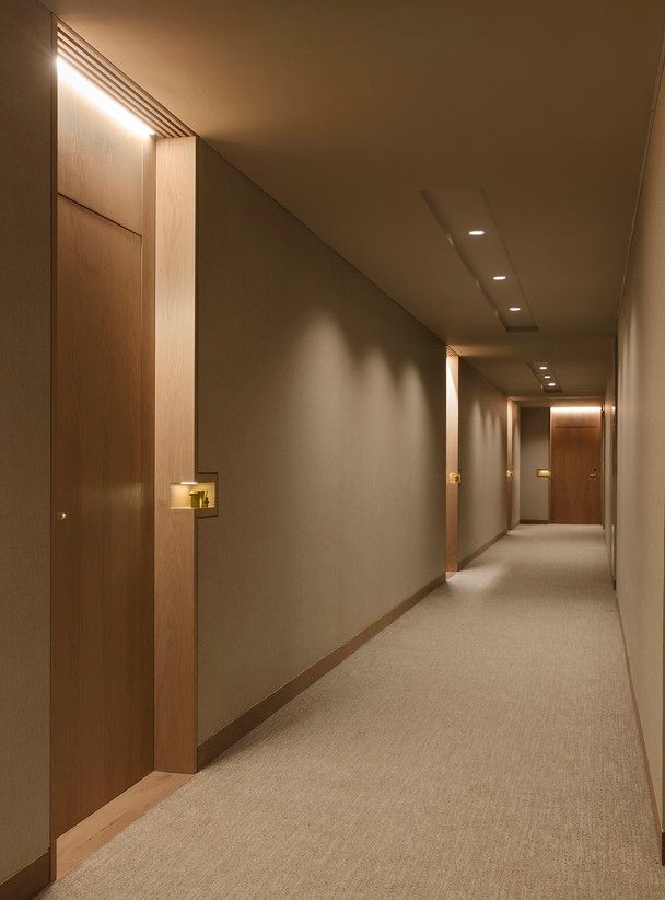 an empty hallway with light wood doors and carpeted flooring is seen in this image