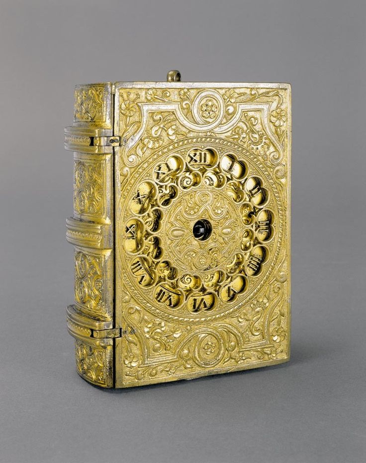 a gold colored box with an intricate design on the front and sides, sitting on a gray surface