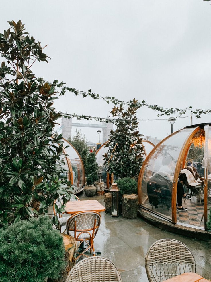 an outdoor restaurant with tables and chairs on the roof terrace, surrounded by greenery