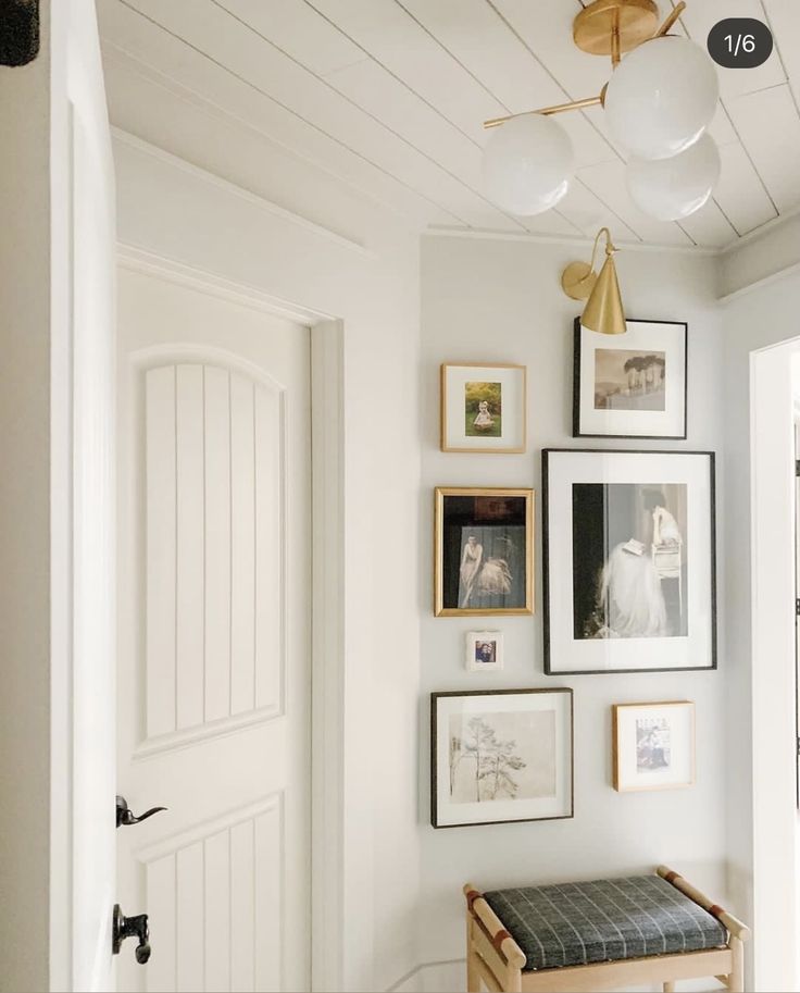 a white room with pictures on the wall and a wooden bench in front of it