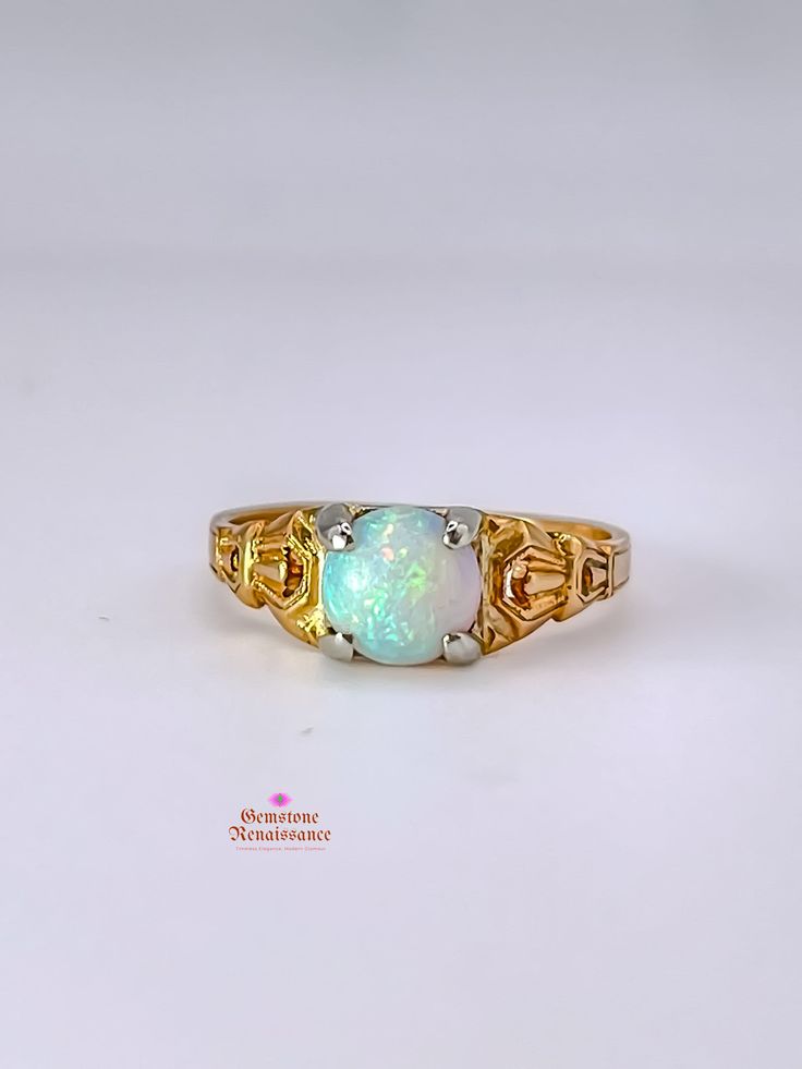 Item Description: This exquisite opal ring is a true gem from the Antique Edwardian/Art Deco period. Crafted in 14K yellow gold with intricate carved detailing on the band, this ring showcases a stunning pale blue opal with captivating red undertones when exposed to light. The single stone opal is cut in a cabochon style, measuring approximately 7mm in width, 7mm in length, and 4mm in depth. The band width is a delicate 1mm at its shortest. Don't miss the opportunity to own a piece of history with this timeless and elegant opal ring. Key Information: - Category: Fine Jewelry - Era: Antique Edwardian/Art Deco Period - Metal: 14K Yellow Gold with White Gold Prongs - Stone: Opal - Stone Shape: Cabochon - Stone Color: Pale Blue with Red Undertones - Size: Approximately 6.5 - Measurements: 7mm Antique Opal Ring, Edwardian Ring, Edwardian Art, Romantic Jewellery, Cabochon Ring, Single Stone, 14k Gold Ring, Opal Ring, Antique Jewellery