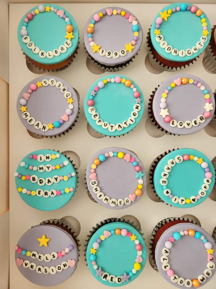 twelve decorated cupcakes are in a box on the table, ready to be eaten