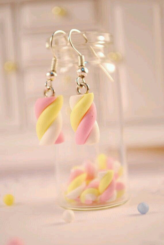 some candy in a glass jar with earrings hanging from it's earwires