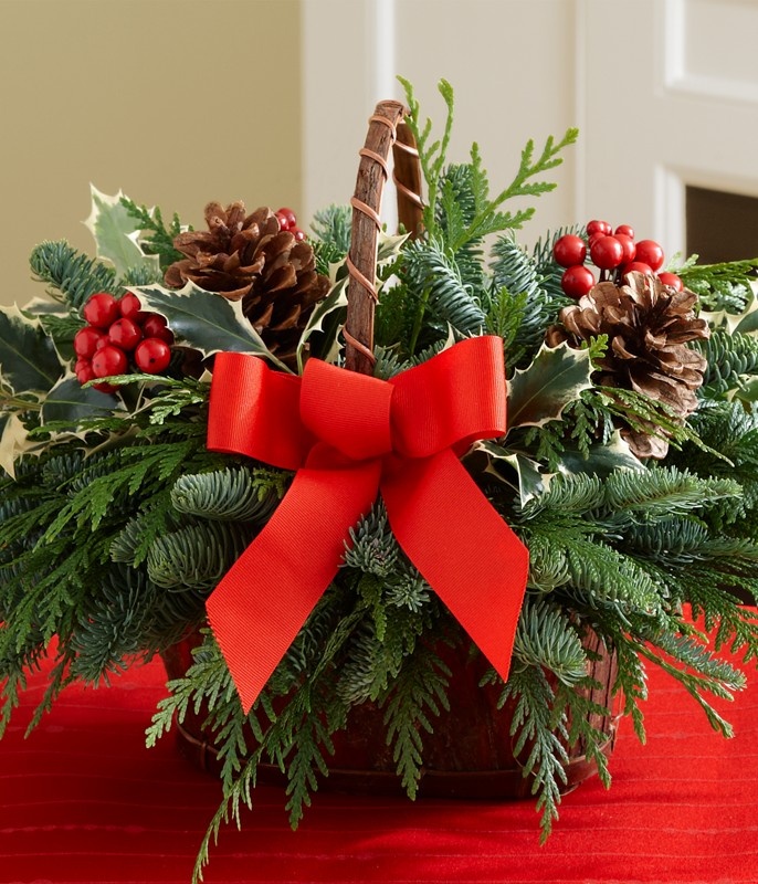 a basket filled with holly and pine cones on top of a red cloth covered table