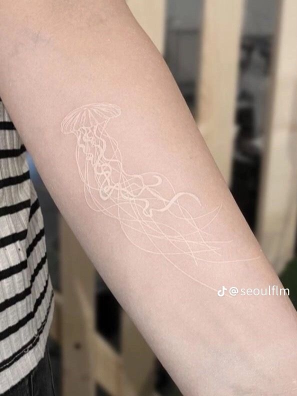 a woman's arm with a tattoo on it that has an image of a jellyfish