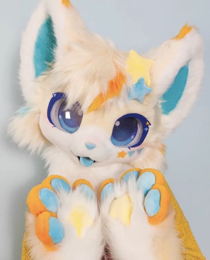 a close up of a stuffed animal with big blue eyes and yellow paws on it's feet