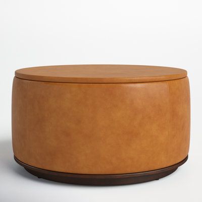 a tan leather ottoman with wooden legs and round top, on a plain white background