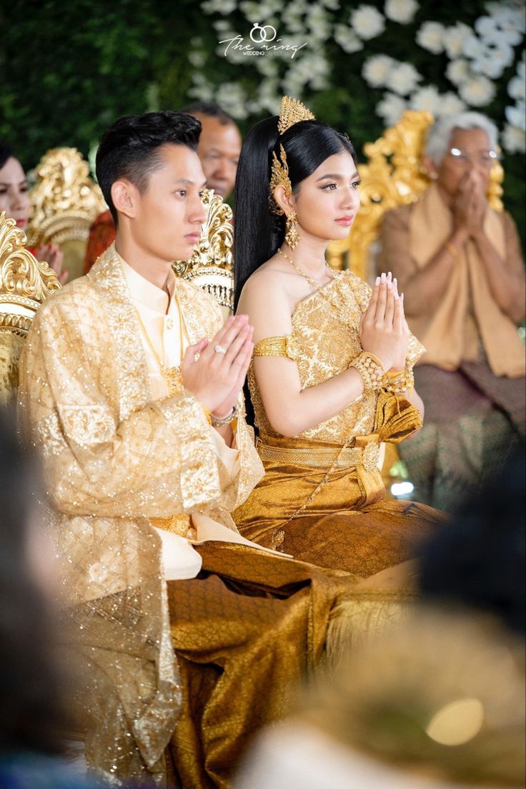 a man and woman sitting next to each other in front of a group of people