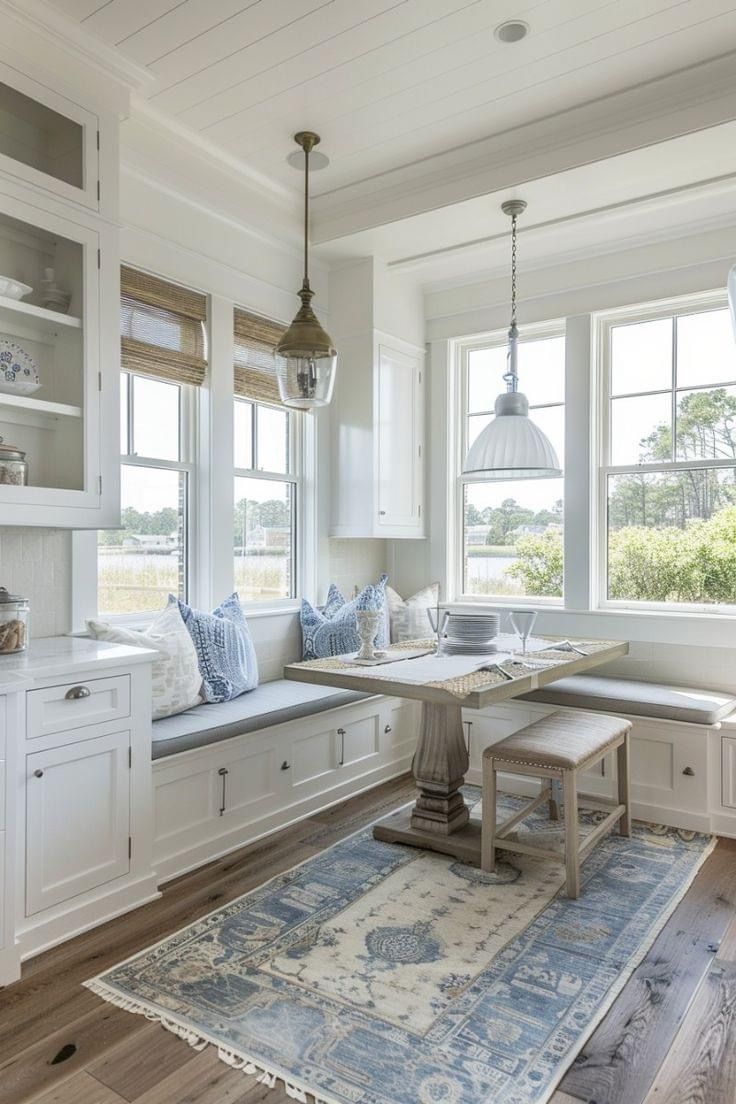 a white kitchen with lots of windows and wooden flooring, along with a rug on the floor