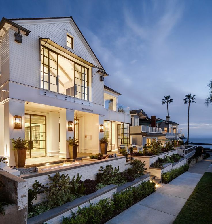 a large white house sitting on top of a lush green hillside next to the ocean