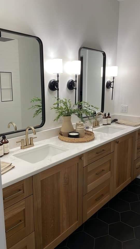 a bathroom with two sinks, mirrors and plants on the counter top in front of them