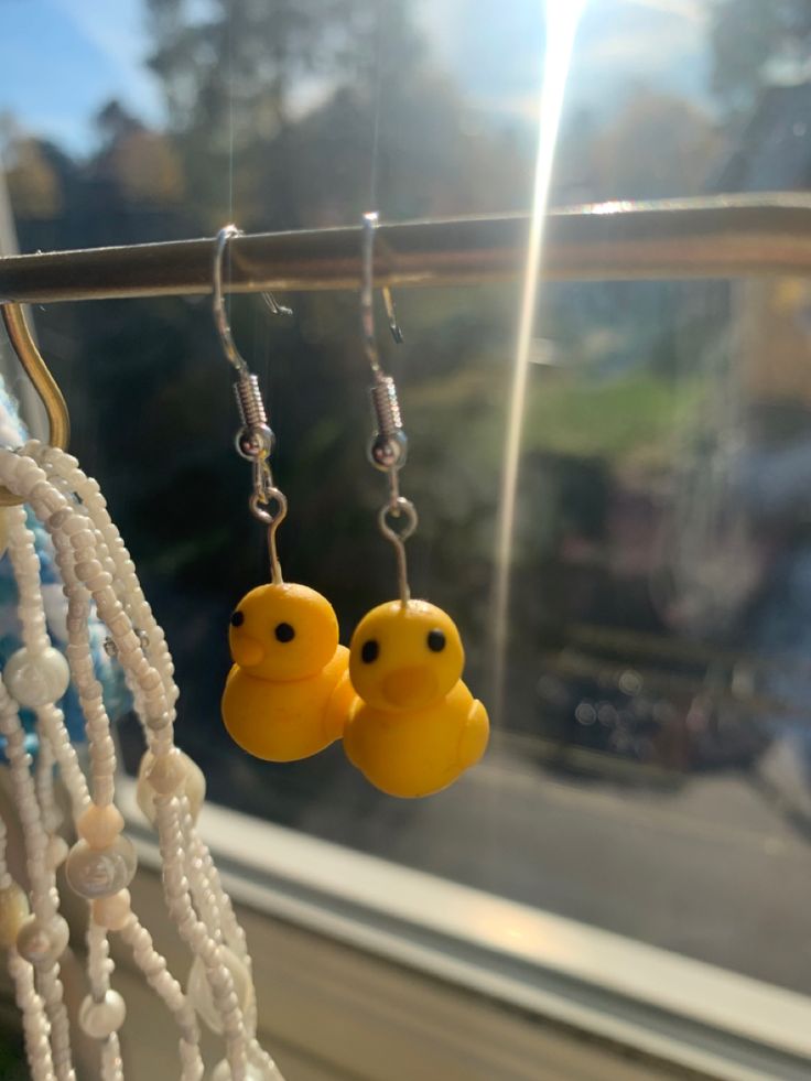 two yellow rubber ducks are hanging from earrings