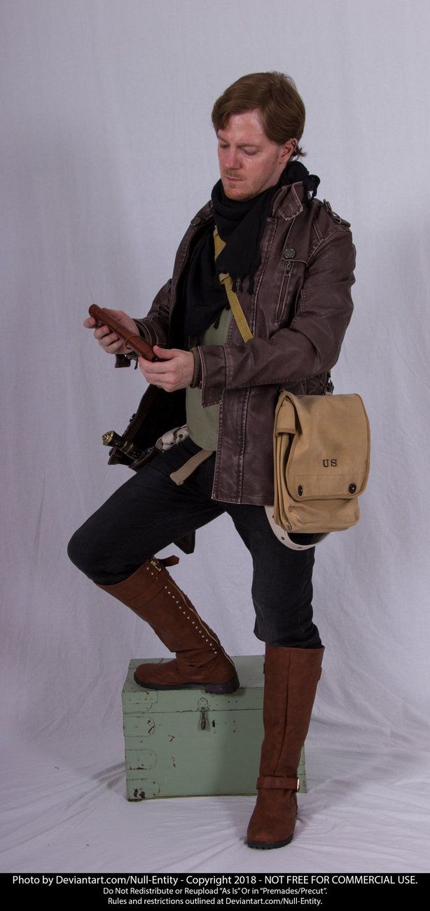 a man sitting on top of a suitcase holding a brown bag and looking at his cell phone