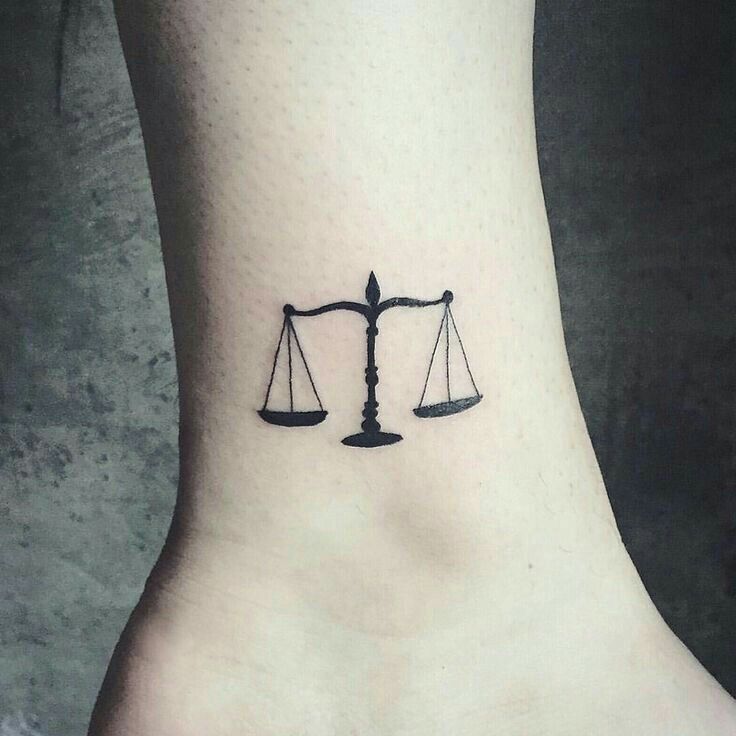 a scale and weight symbol tattoo on the ankle