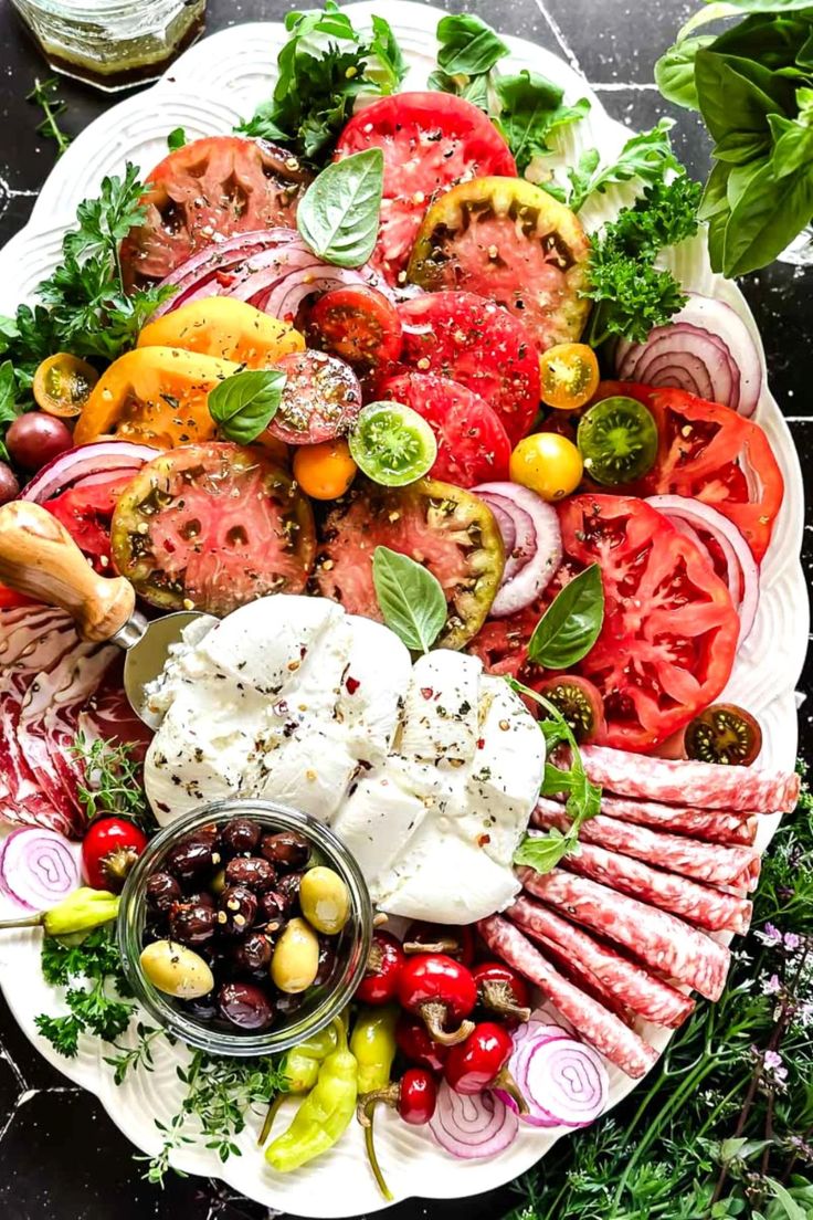 a platter filled with tomatoes, olives, onions, and other veggies