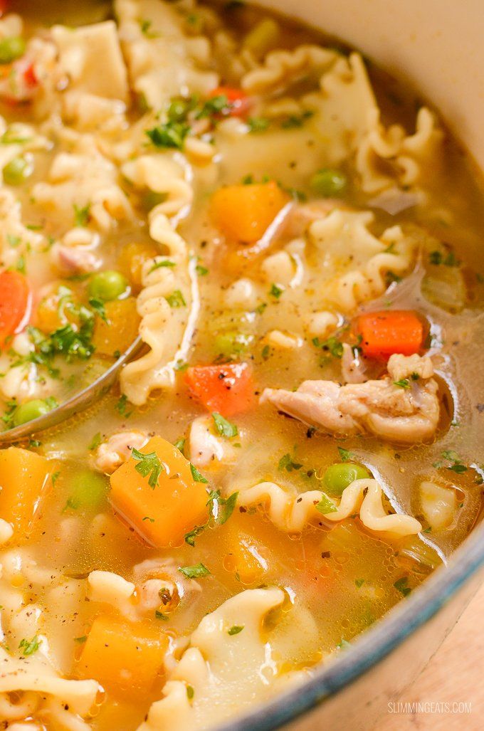 a bowl filled with chicken noodle soup on top of a wooden table