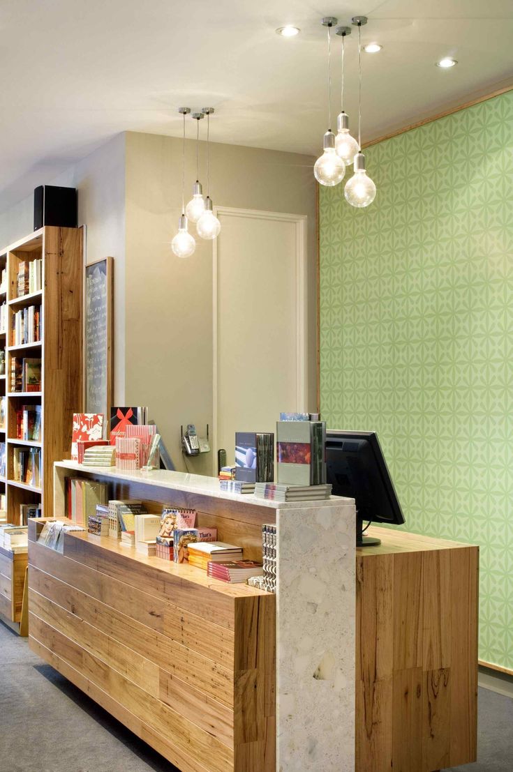 the front desk of a library with bookshelves in the background and lights hanging from the ceiling