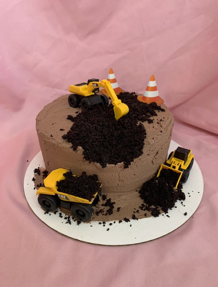 a chocolate cake with construction trucks on top and dirt in the middle, sitting on a white plate