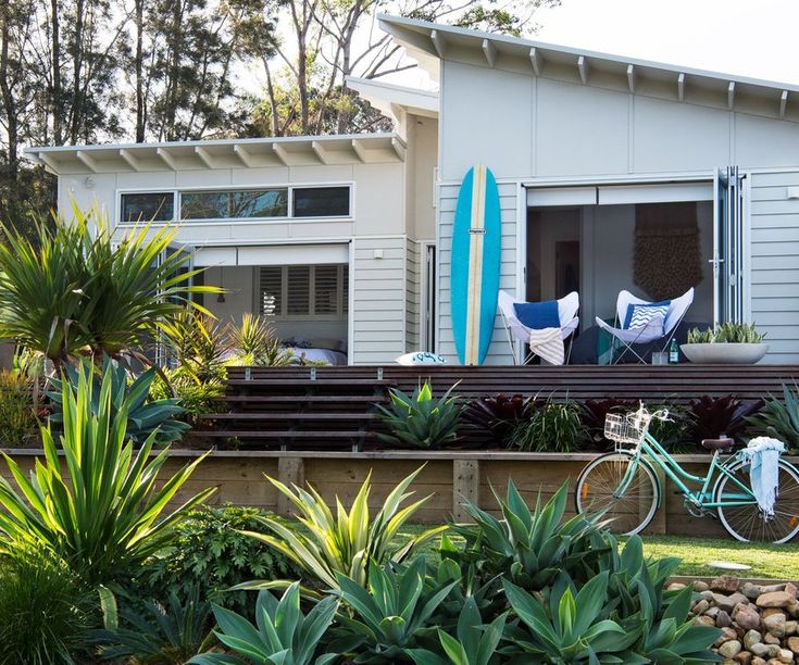 there is a blue bike parked in front of a house with two surfboards on the porch