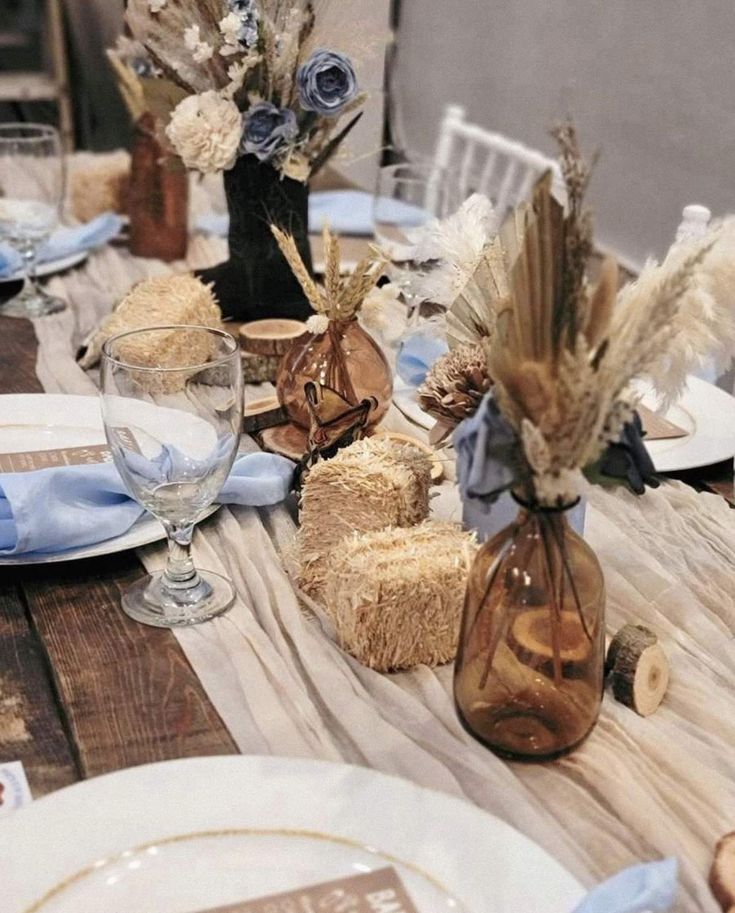 a wooden table topped with plates and vases filled with flowers next to other place settings