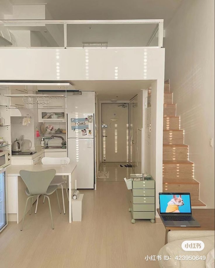 a laptop computer sitting on top of a wooden table next to a white kitchen and living room