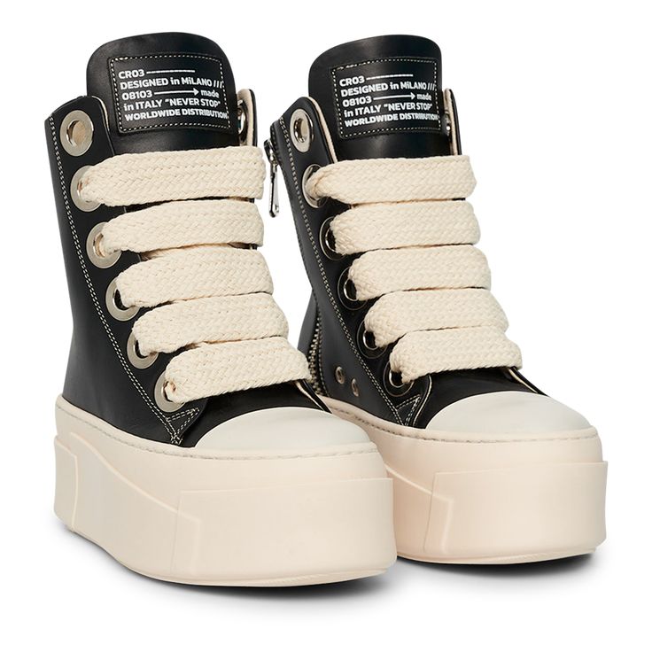 The sneakers are high-top platform-style shoes with a dominant color scheme of black and cream. They feature a thick, cream-colored rubber sole with layered detailing that gives the shoe a bold and chunky silhouette. The upper part of the sneakers is primarily black, constructed with leather material. The design includes metal eyelets for the laces, which are cream-colored and chunky, complementing the sole. Chunky Black Shoes, Wishlist Shoes, High Top Tennis Shoes, High Platform Shoes, Curvy Casual Outfits, Chunky Platform Sneakers, Silly Clothes, Men Boot, Dr Shoes