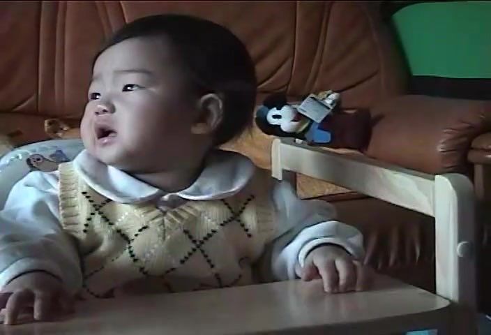 a baby sitting in a highchair with his mouth open and hands on the table