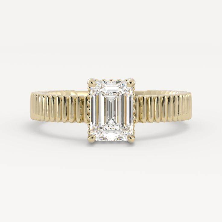 a yellow gold engagement ring with an emerald cut diamond in the center and thin band