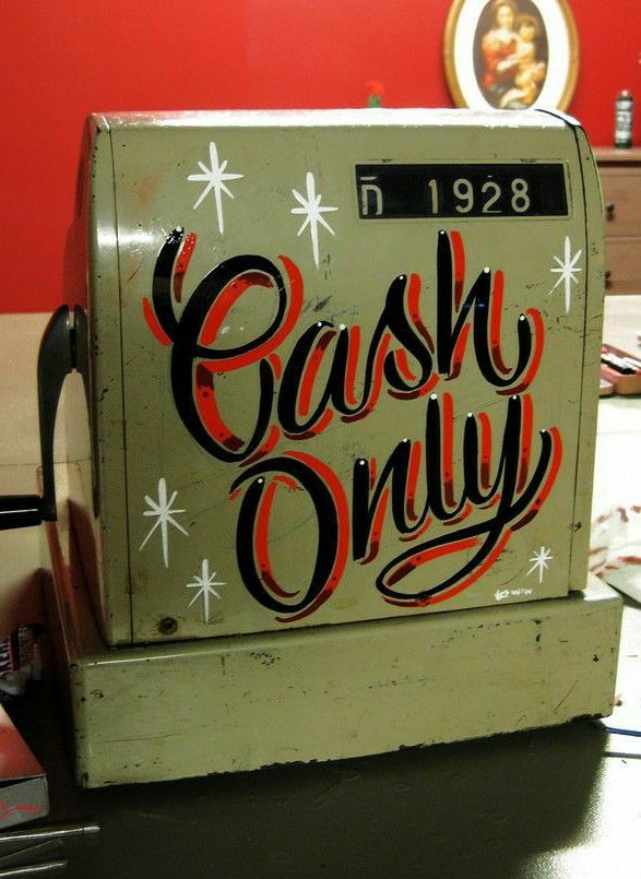 an old cash register sitting on top of a table in front of a red wall