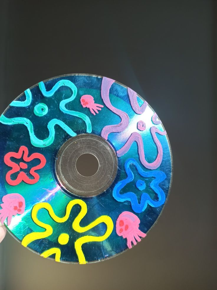 a person holding up a cd with colorful designs on it