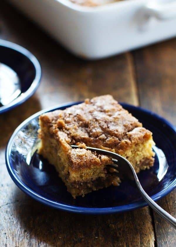 a piece of cake on a blue plate with a fork in it and a casserole dish to the side