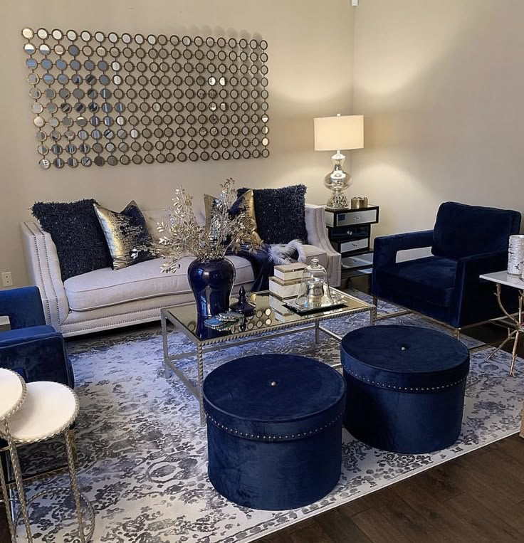 a living room with blue velvet furniture and mirrors on the wall above it's windows