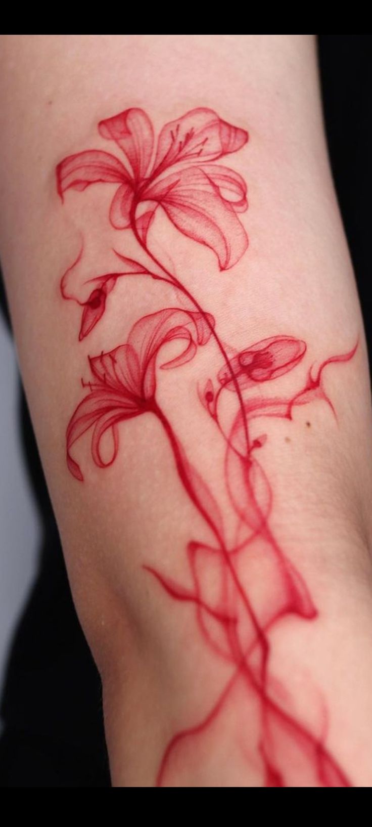 a tattoo with red ink on the side of a woman's arm and flowers growing out of it