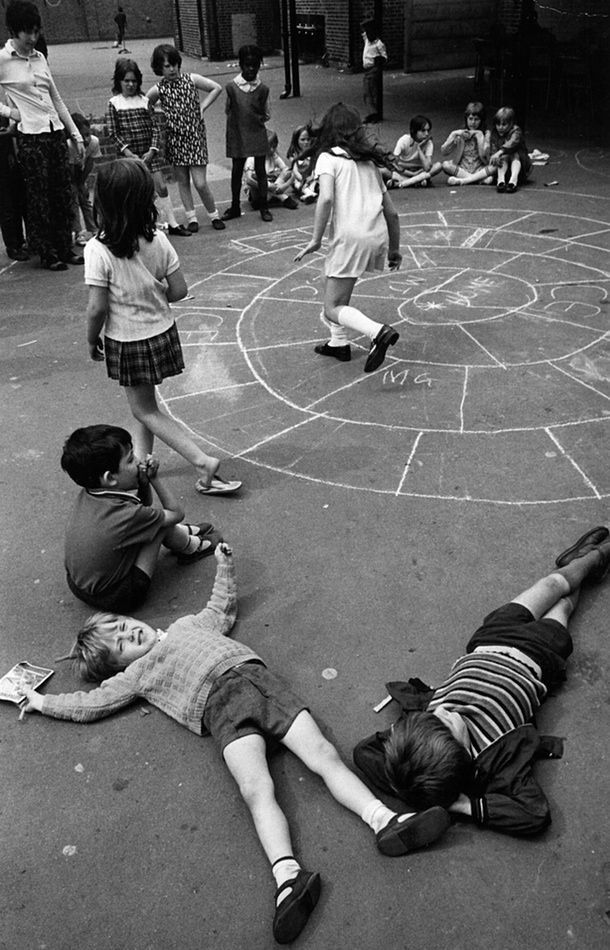 several children are playing on the ground in a circle with chalk drawings drawn on it