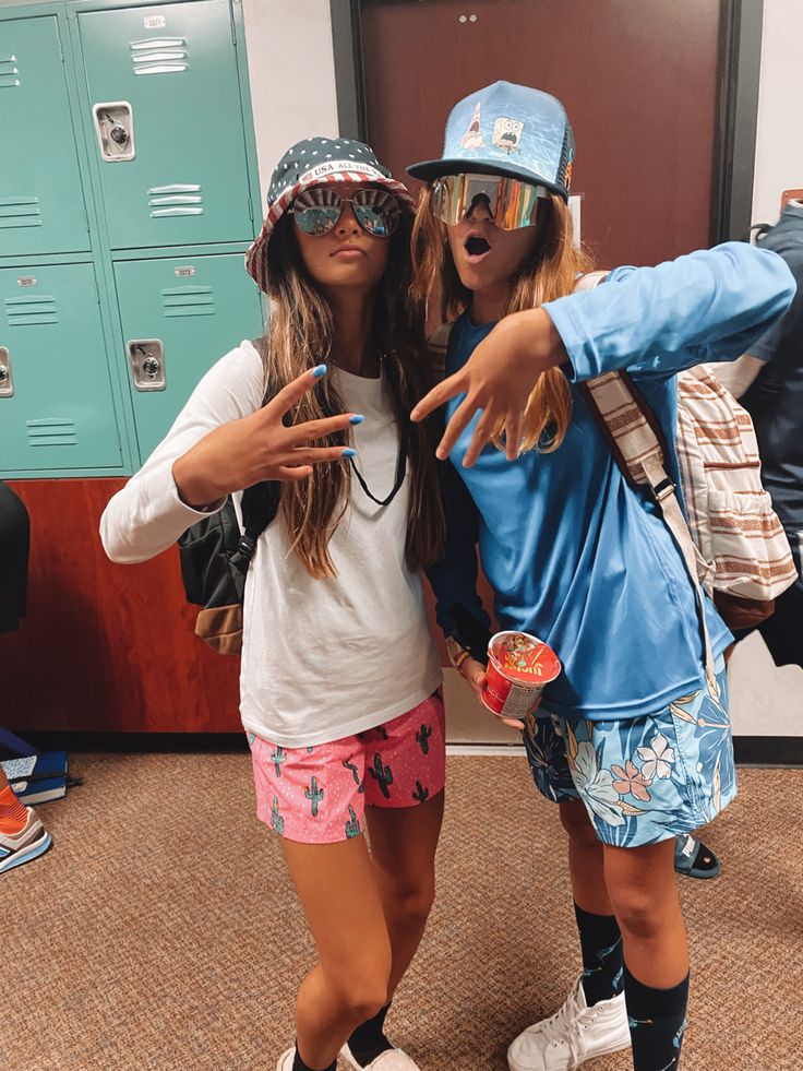 two young women standing next to each other in front of lockers with one pointing at the camera