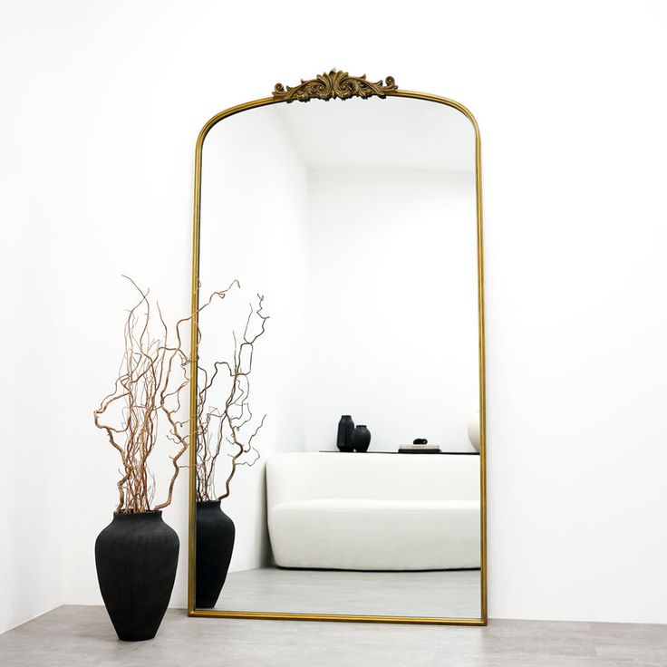 a large mirror sitting on top of a table next to a vase