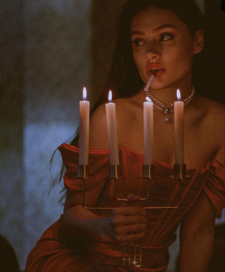 a woman in a red dress with candles on her face and one candle sticking out of her mouth