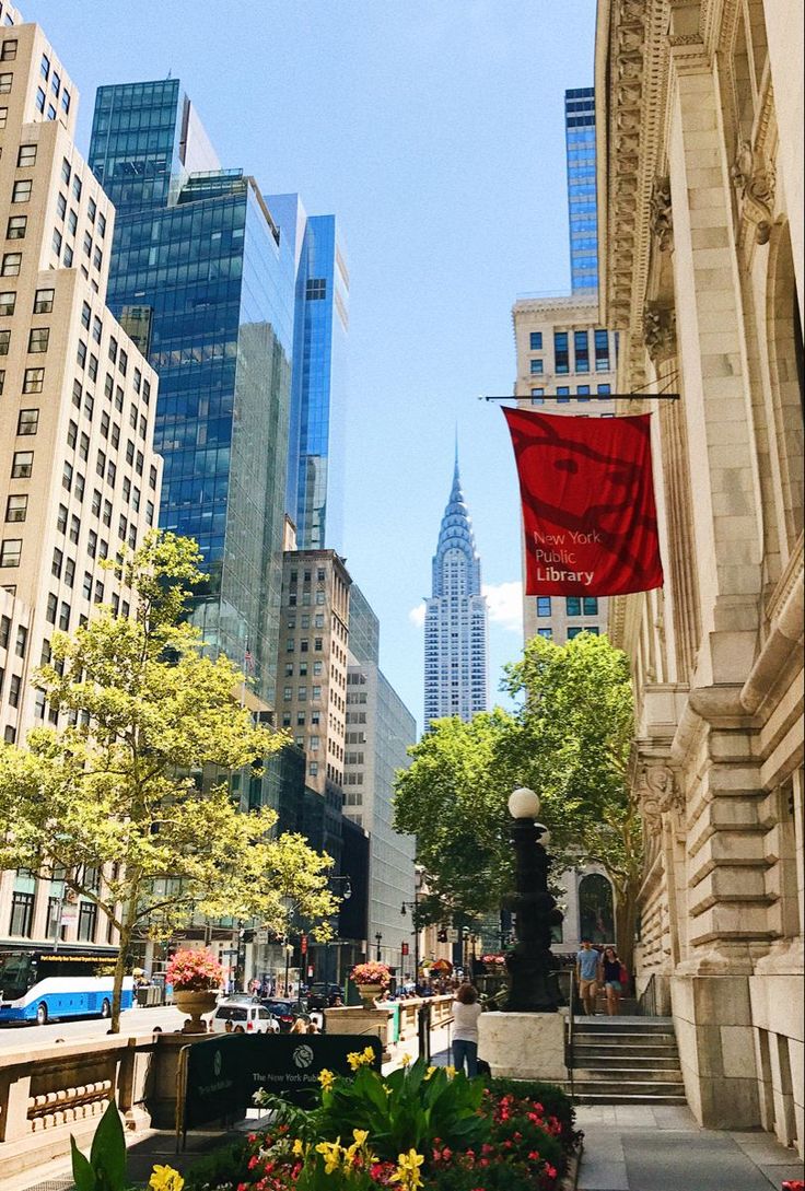 a city street with tall buildings and flowers in the foreground, on a sunny day