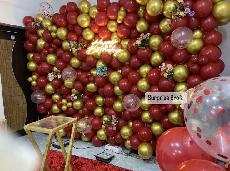 the balloon wall is decorated with red and gold balloons